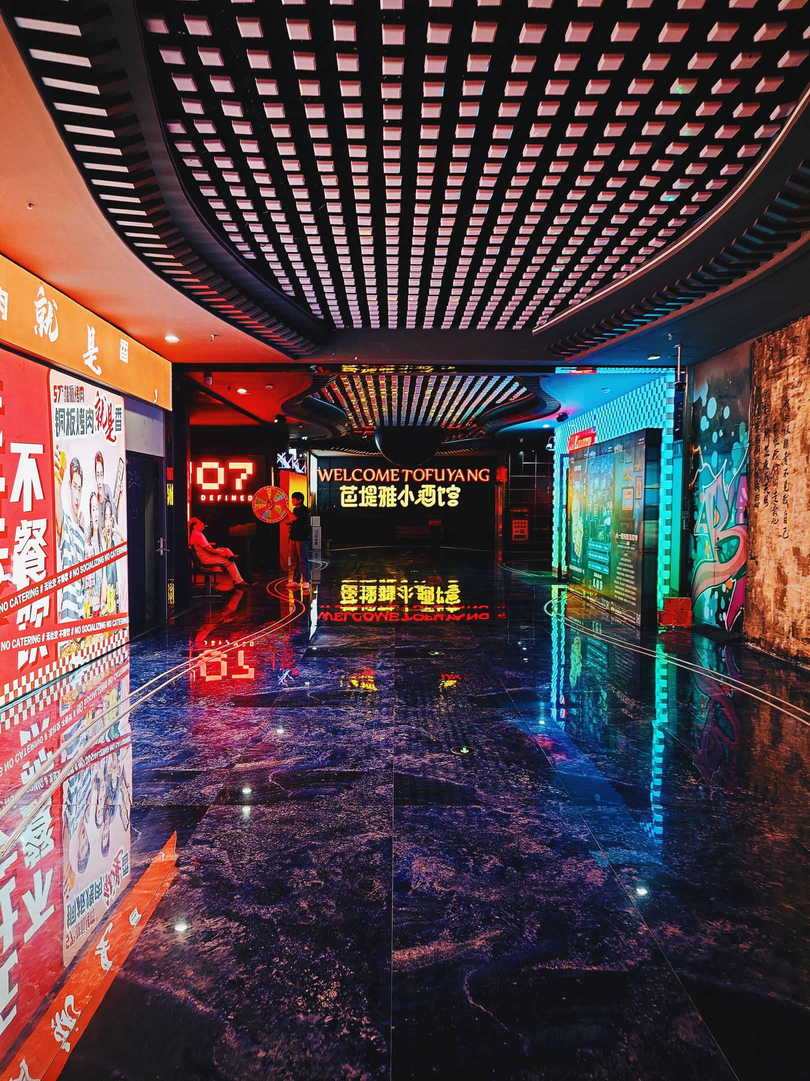 Shopping mall entrance with lights and marble floor. Illuminated sign at the end of the hallway reads &lsquo;Welcome to Fùyáng&rsquo;.