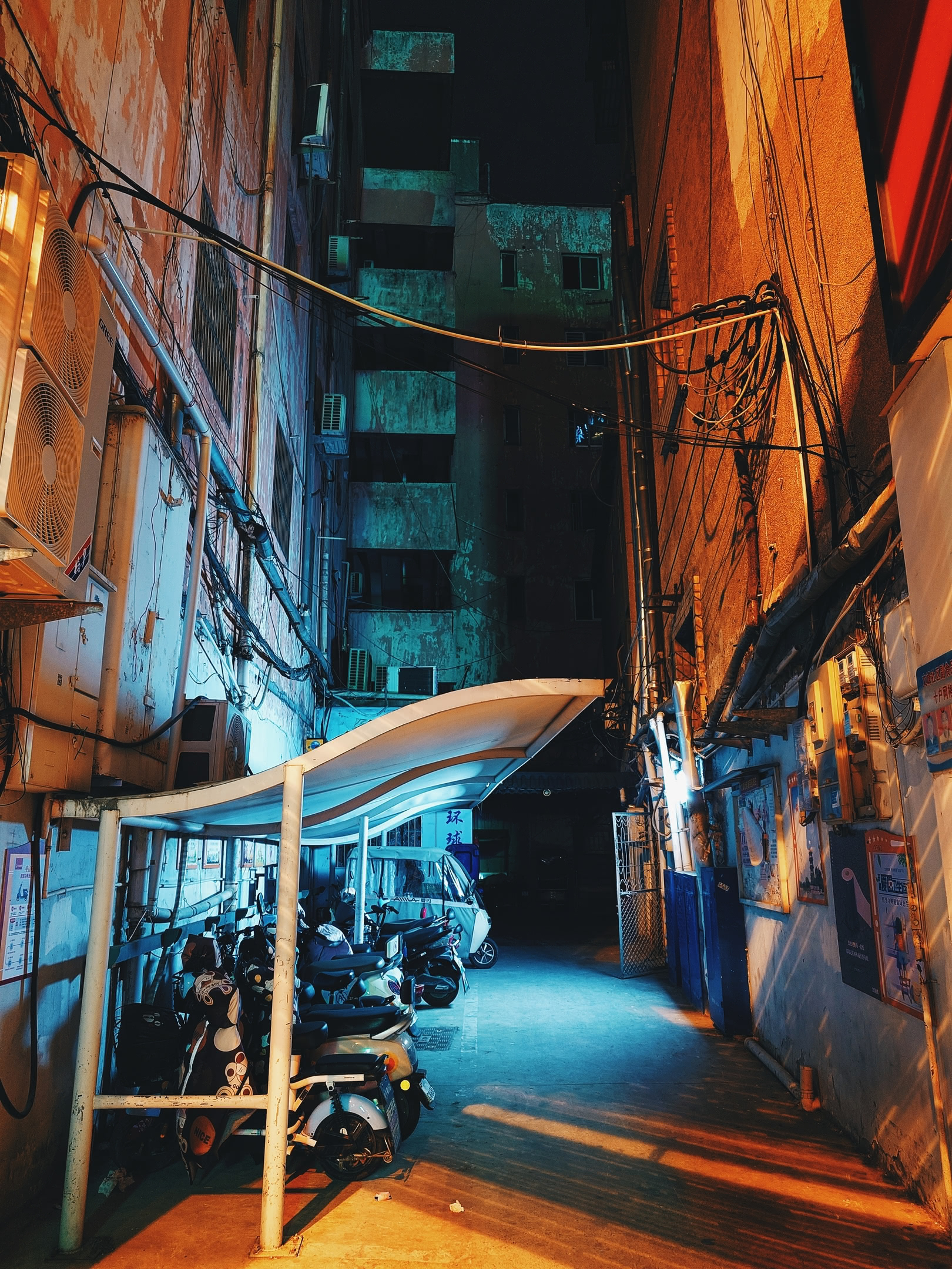 Small residential alleyway with e-bikes at night.