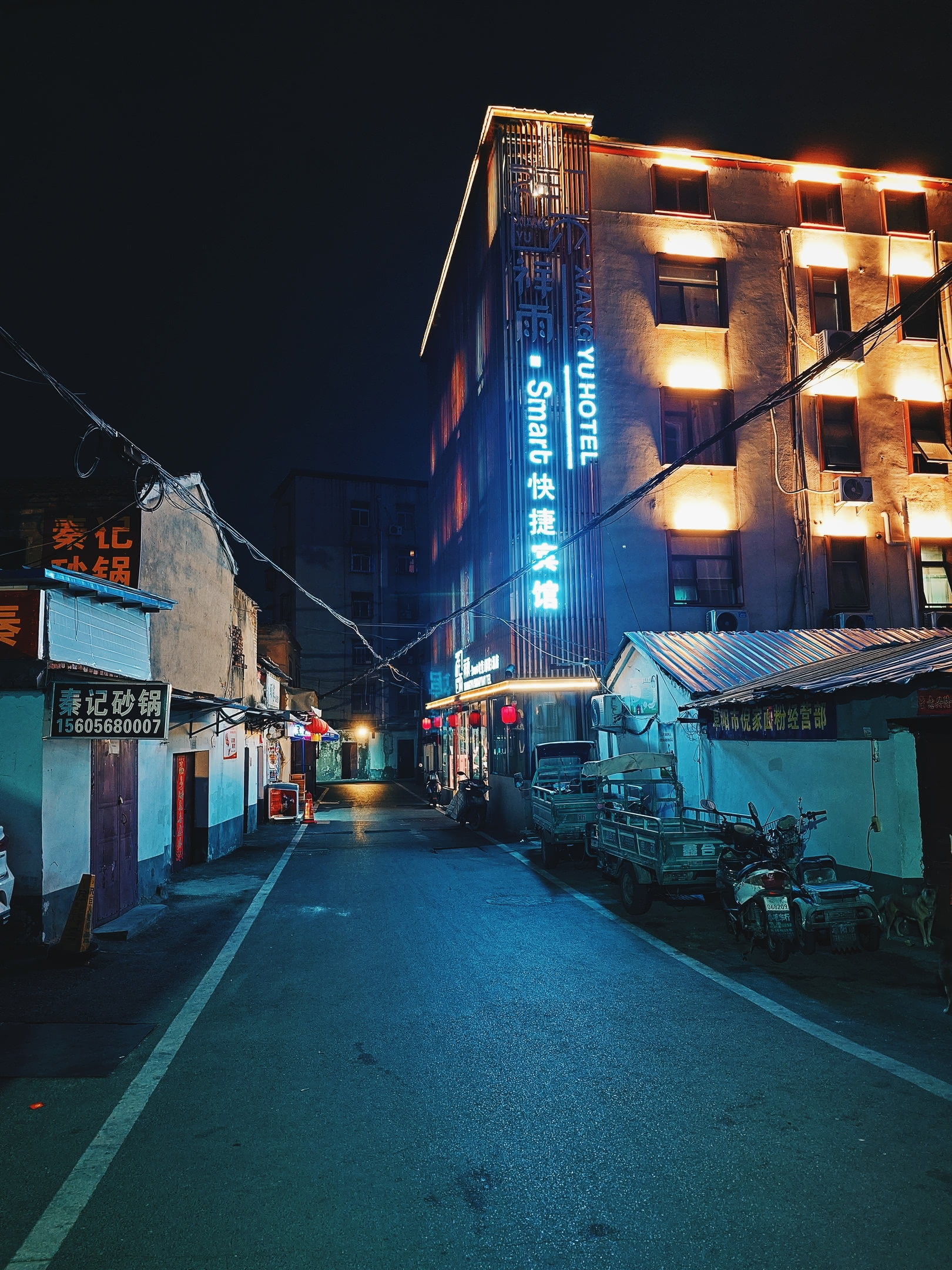 Alleyway at night with hotel and closed storefronts.