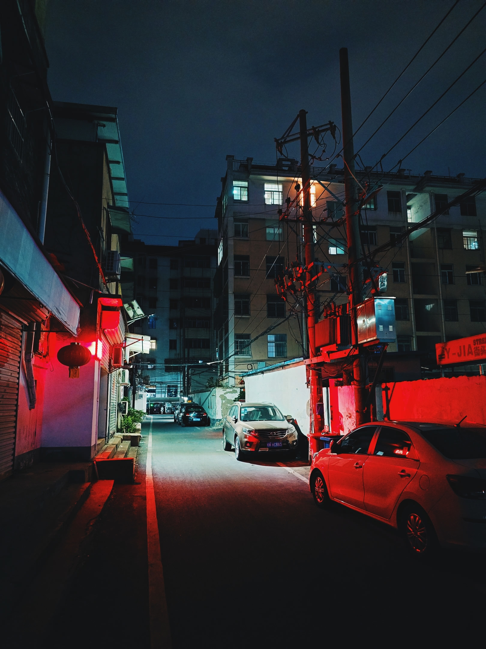 Residential side-street at night lit by red light.