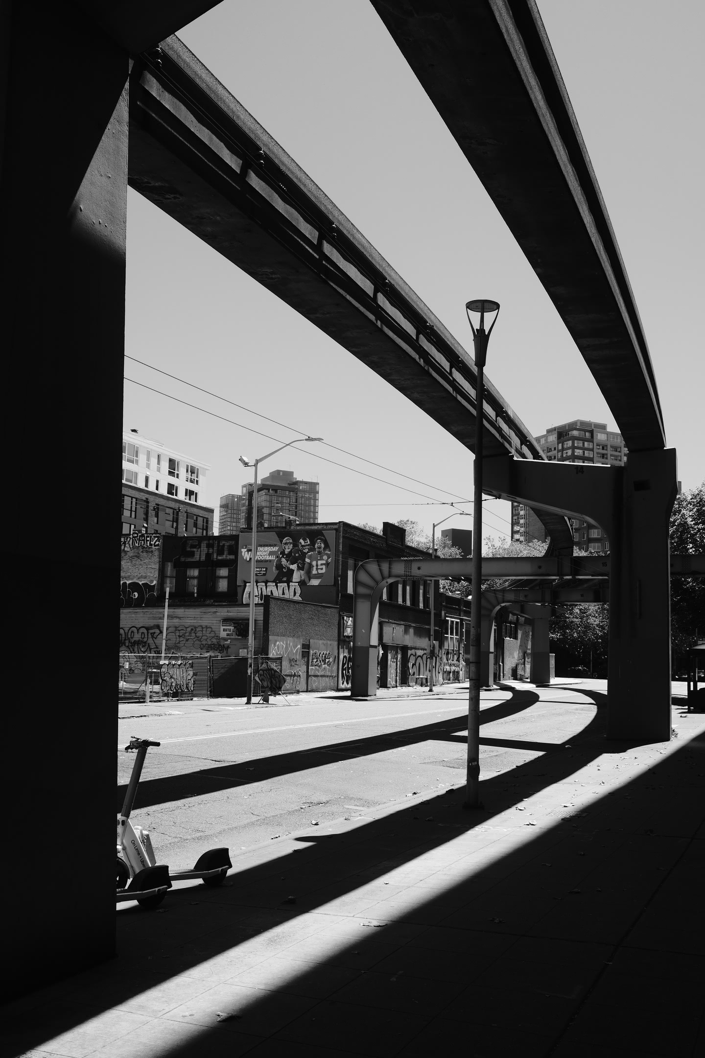 Hard mid-day shadows cast across a road by a monorail line.