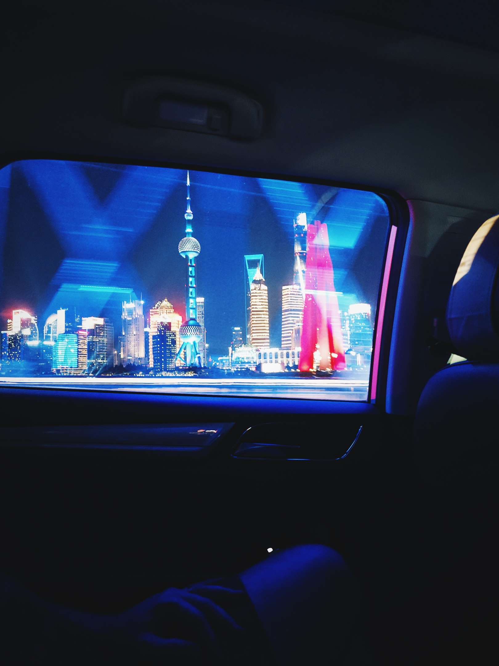 Lùjiāzuǐ skyscrapers illuminated at night. Taken from the interior of a moving taxi while crossing a bridge.