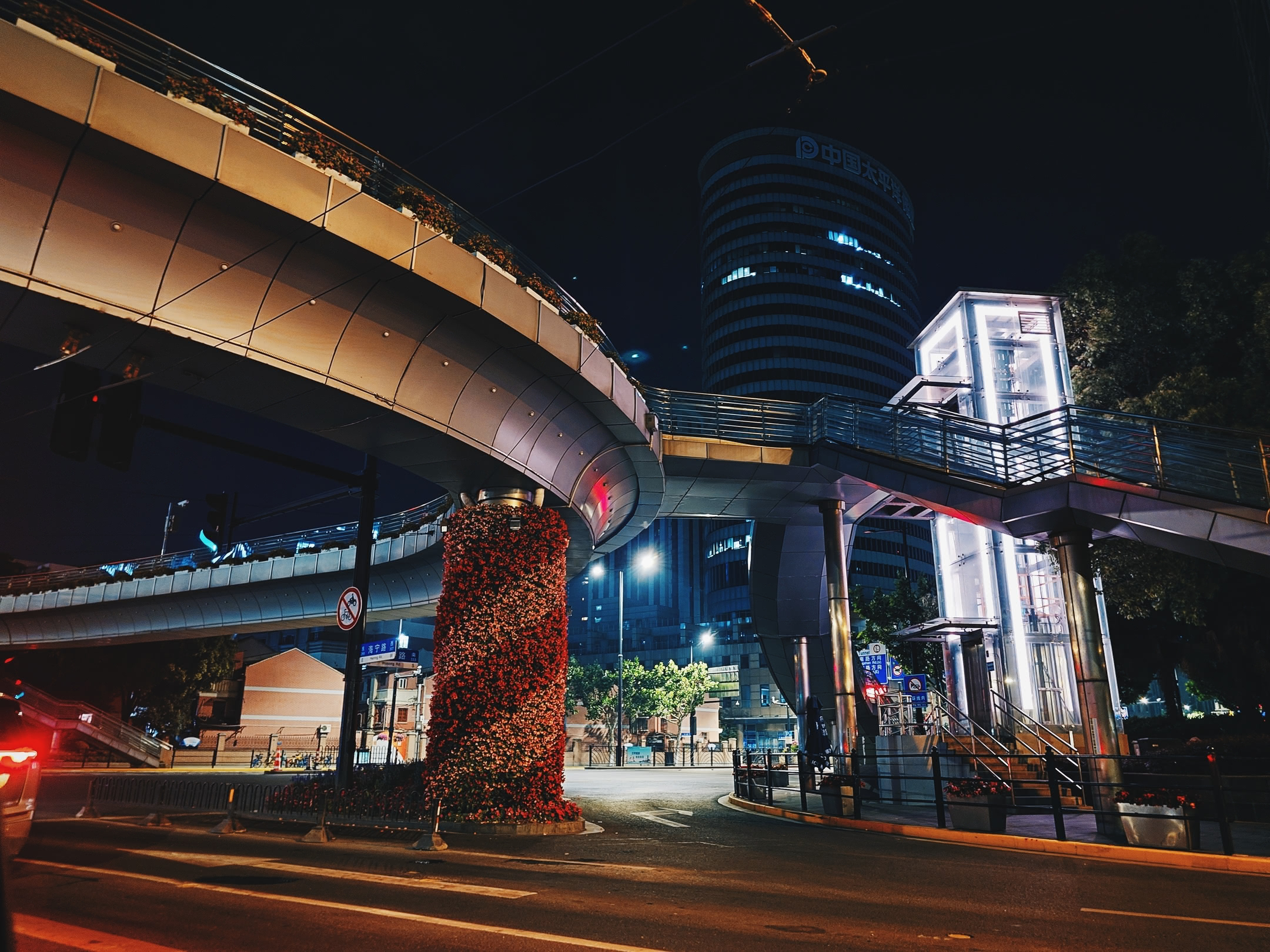 Circular pedestrian walkway above an intersection. At night.