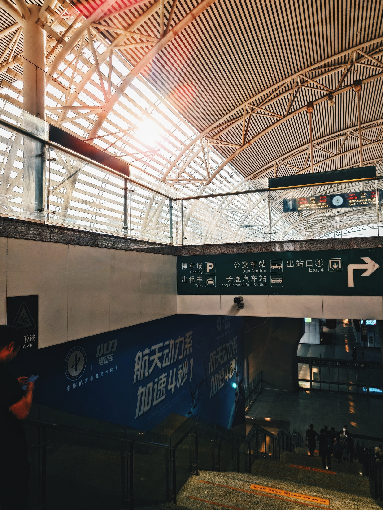 Descending down the stairs of Wúxī train station platform. Gold afternoon sunlight.