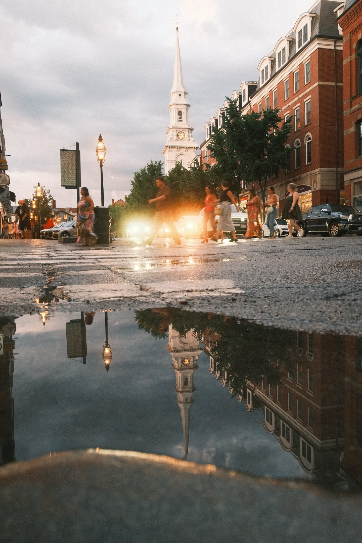 Church reflected off a puddle as pedestrians cross a street after the storms passed.